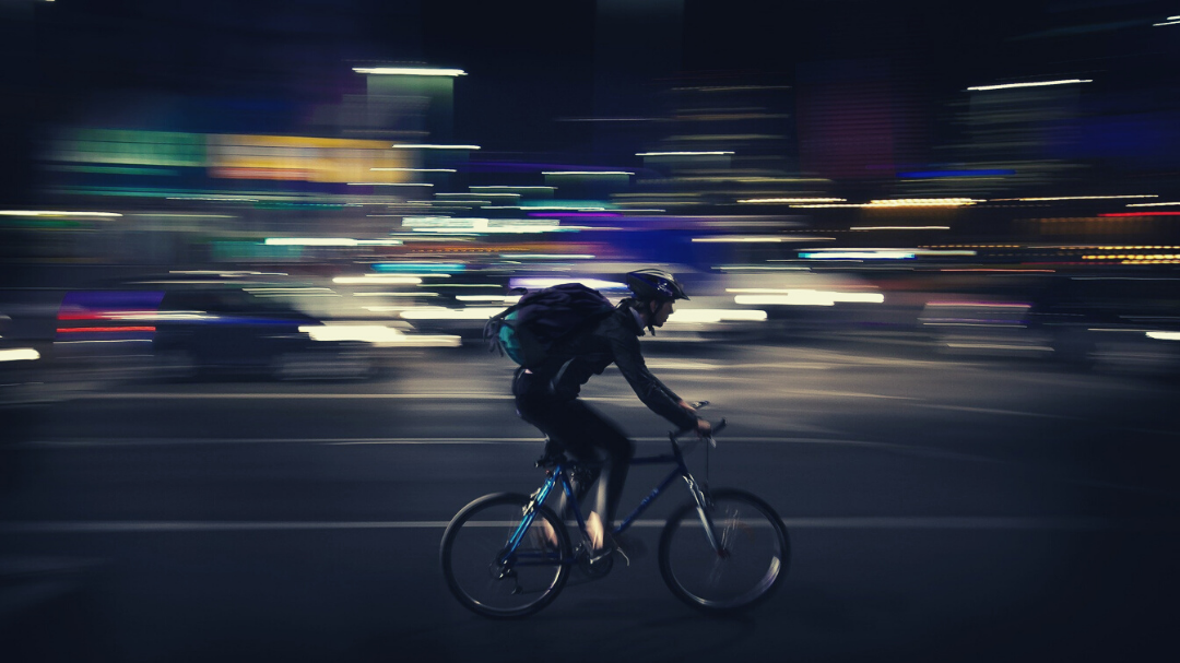 Courier on bicycle, speeding through city at night