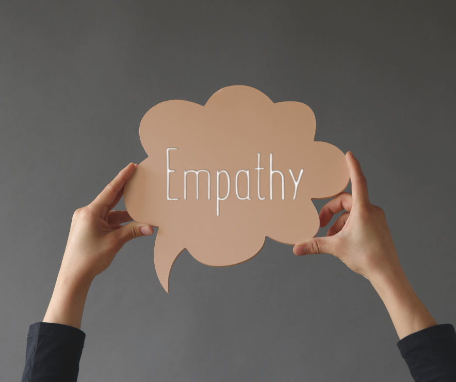 Woman holds up a brown cardboard speech bubble stating "Empathy"