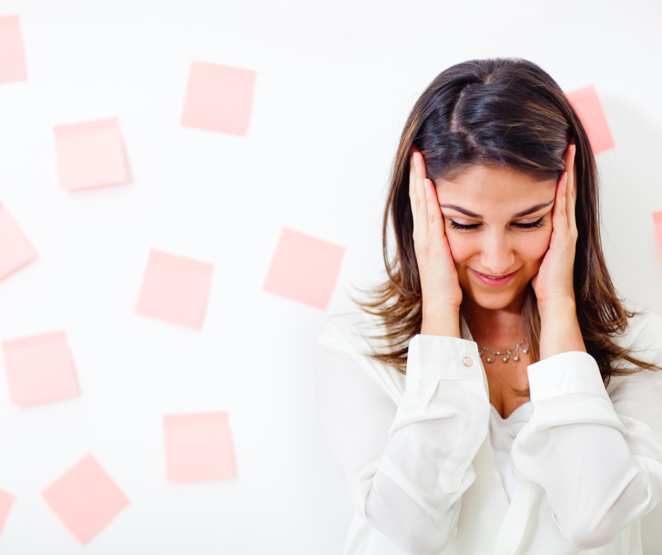 Female counsellor stood with head in hands in front of a wall of post-it notes