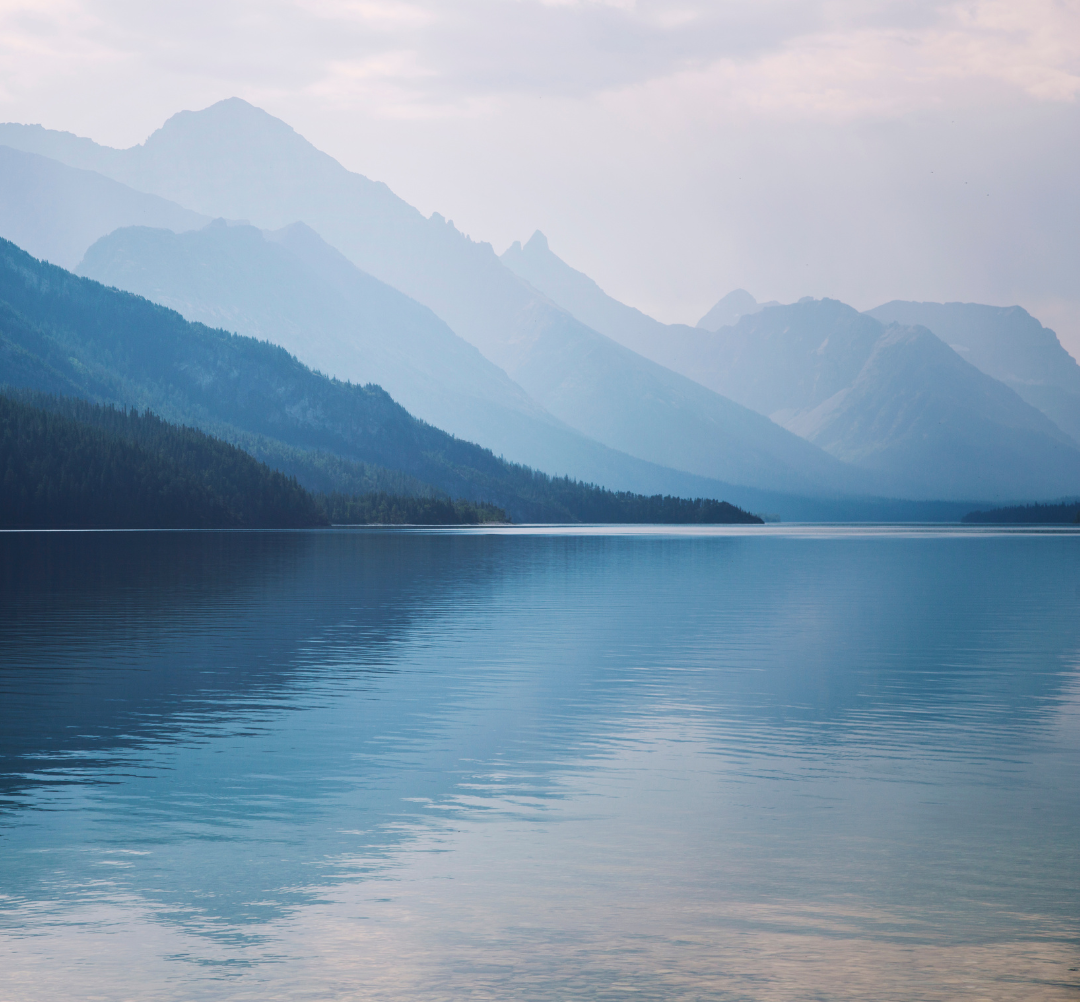 Calm, blue lake in front of blue mountains