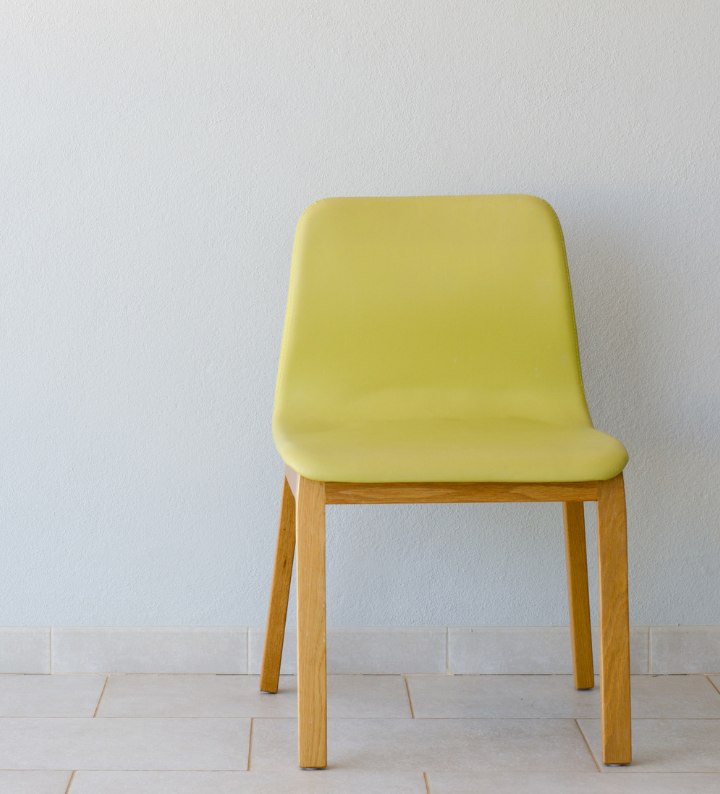 Empty yellow chair against a grey wall