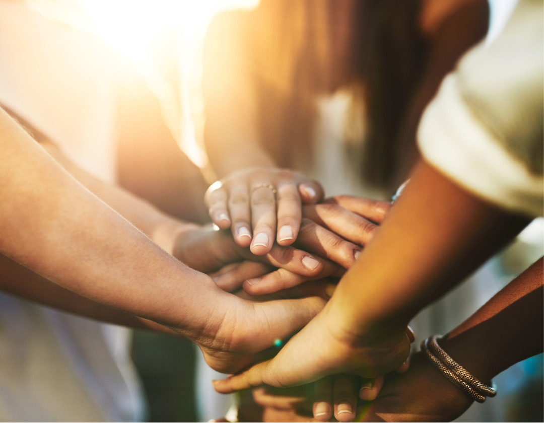 Close up of women's hands placed on top of each others in a circle 