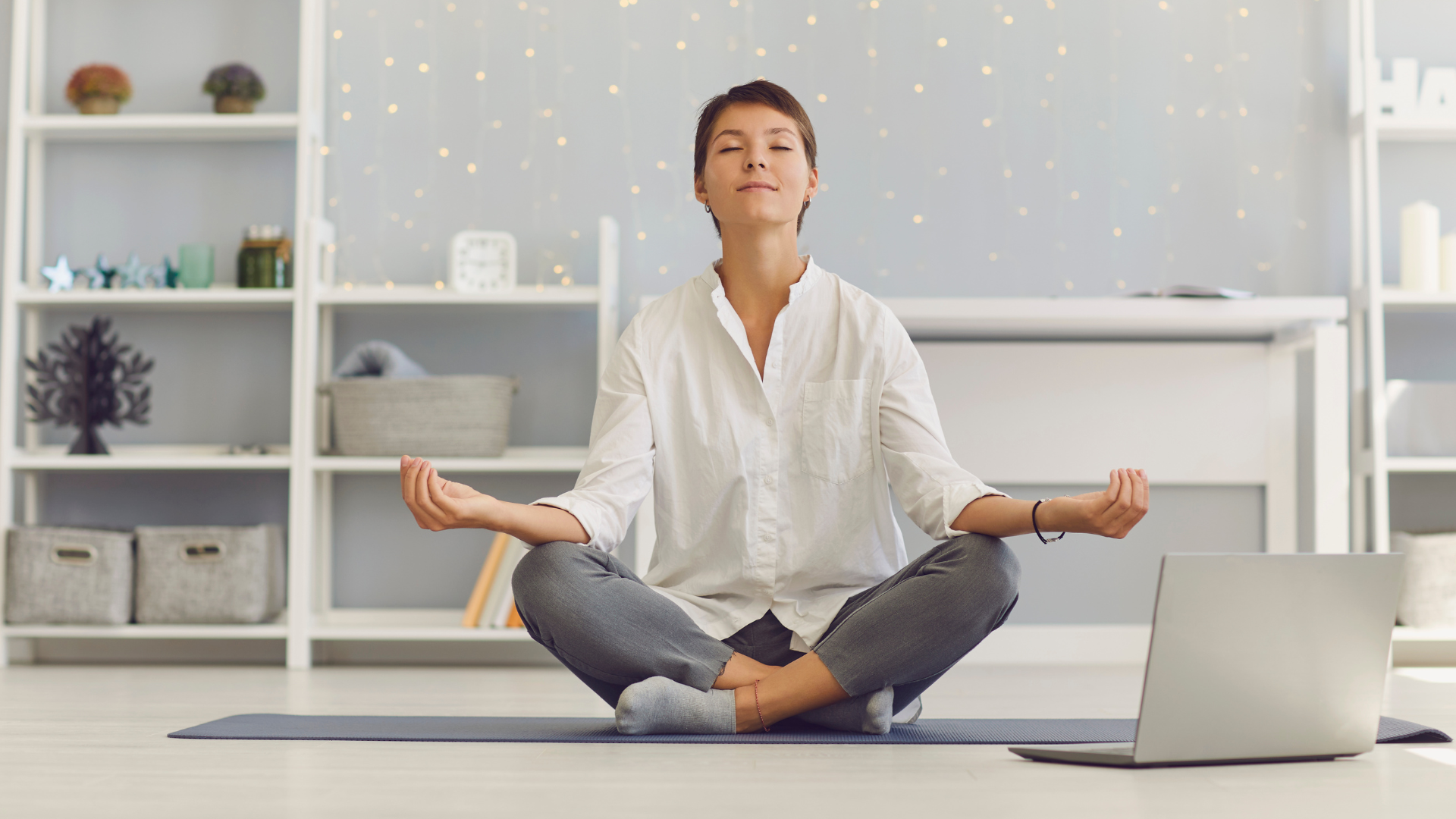 Female therapist sits in lotus position by her laptop