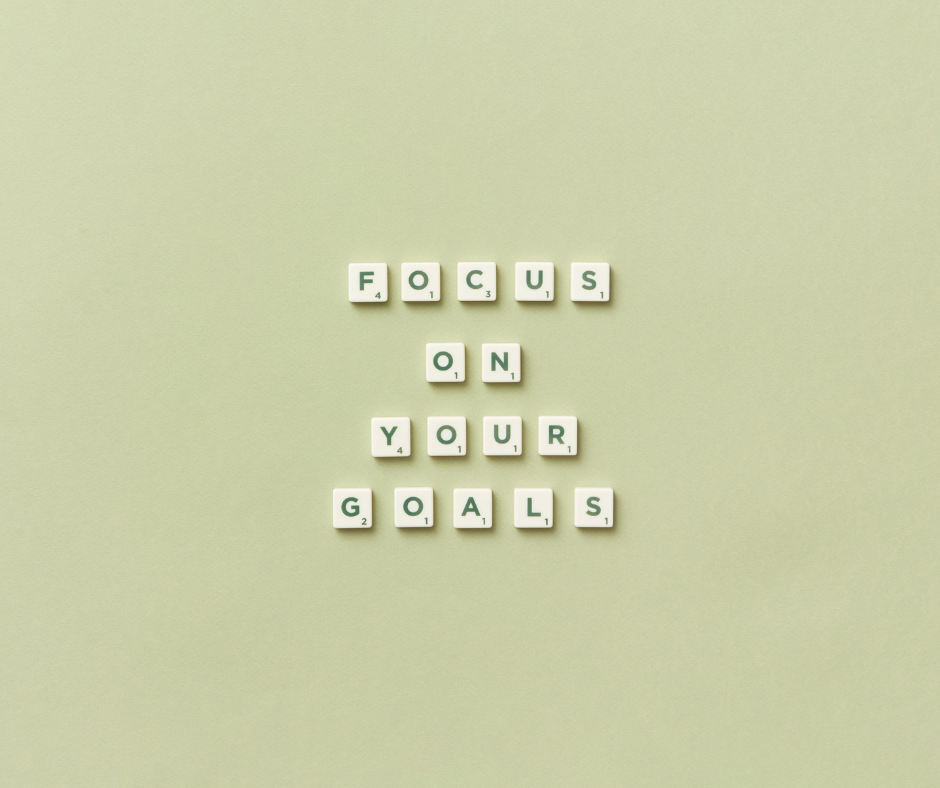 Scrabble tiles spell out "Focus on your goals" against a muted green background