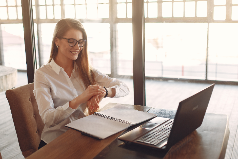 A happy female counsellor sits at her desk whilst looking at her watch