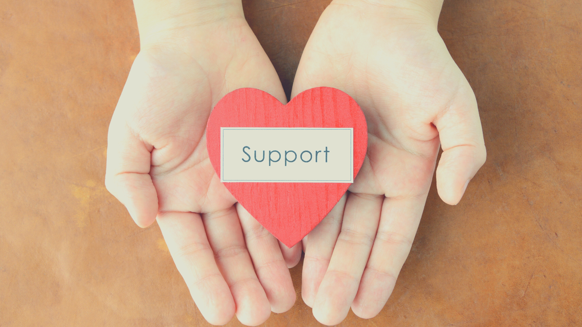 Hands holding a red cardboard heart with the word support written on it representing clinical counselling support