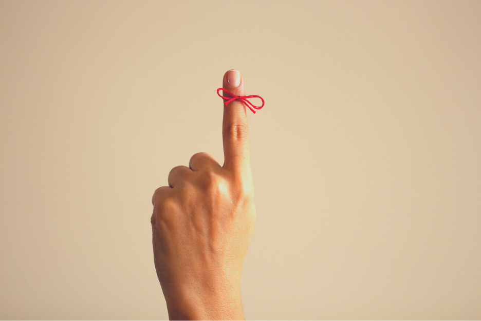 Close up of a hand with a red piece of string tied on the index finger