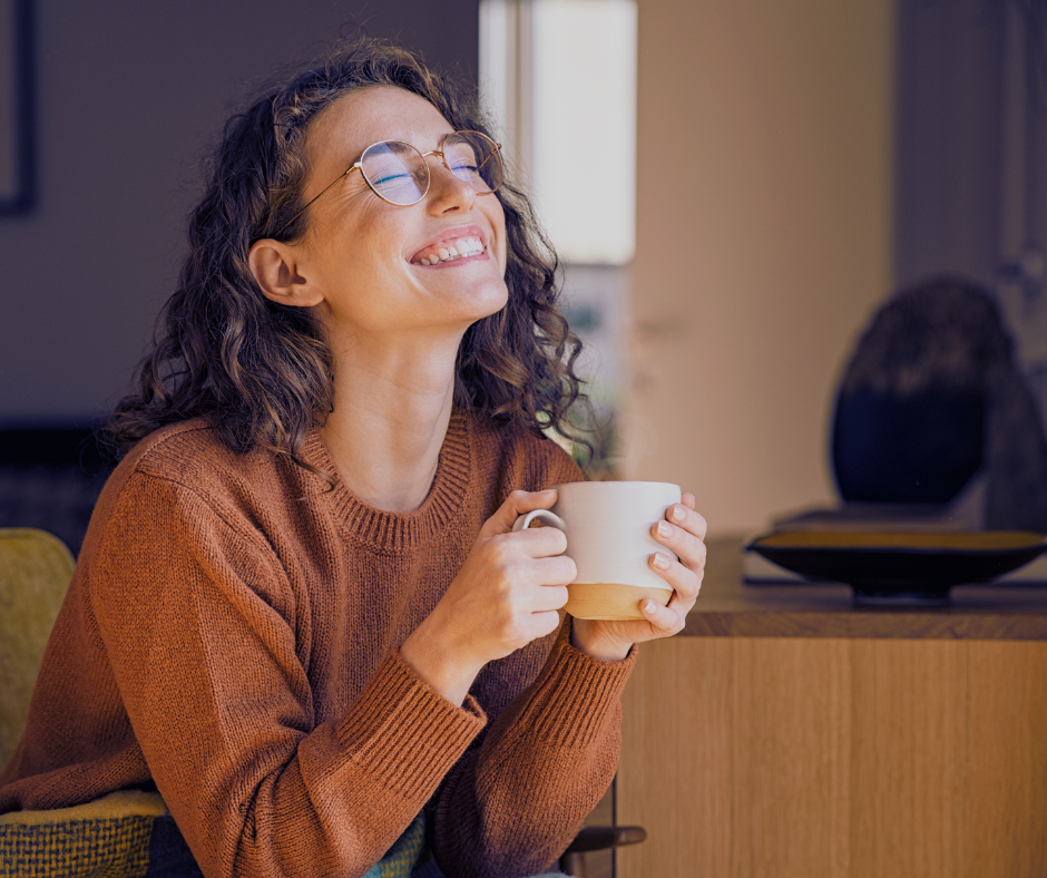 Happy woman smiling as she holds a cup of tea