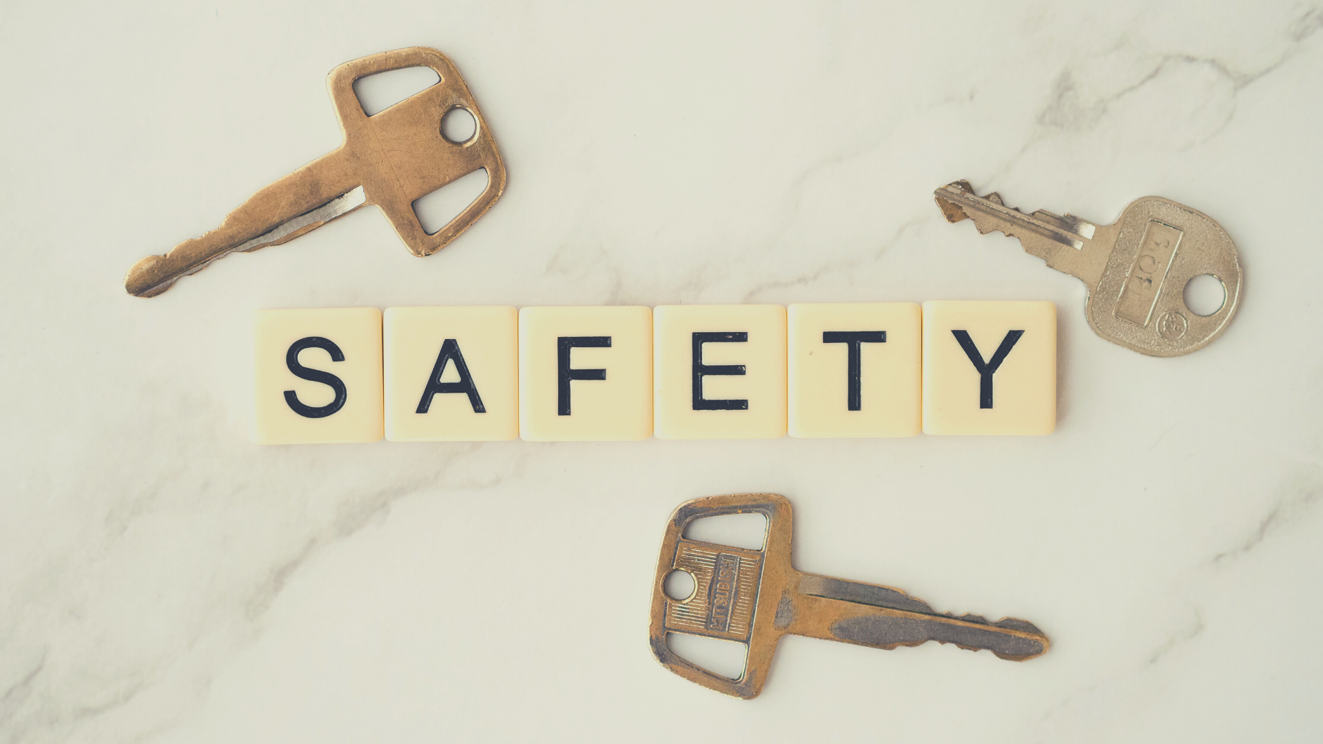 Safety spelled out in scrabble tiles with three old keys placed around it