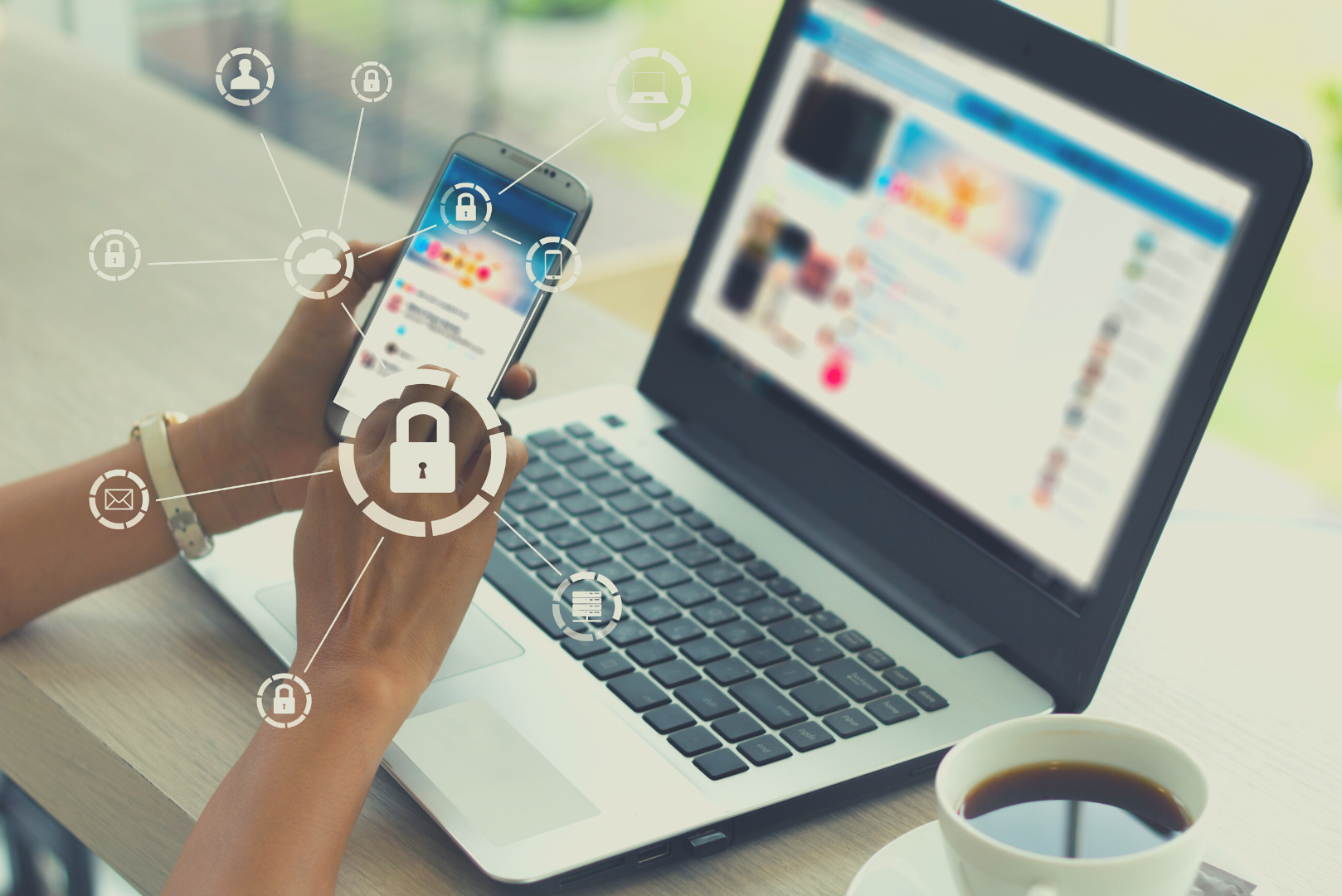 Close up of woman at desk with laptop and a cup of coffee. She is using her phone to access her practice management software via 2FA security. White padlock icons are overlaid to symbolise this.