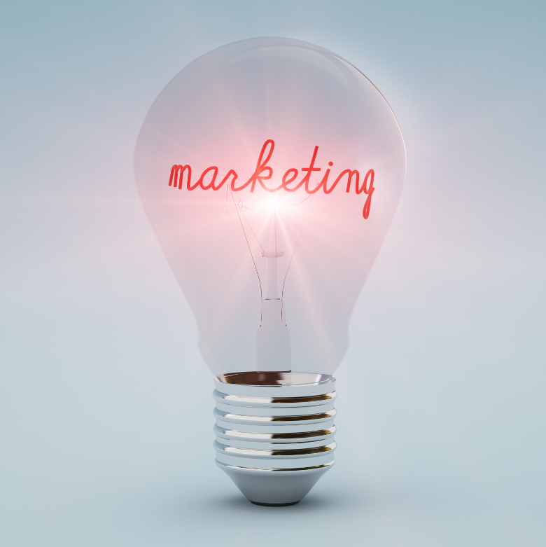 Close up of a lightbulb with marketing written in red script on it, against a pale blue background