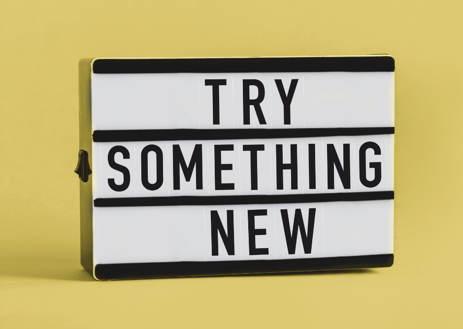 Sign against a yellow background saying TRY SOMETHING NEW