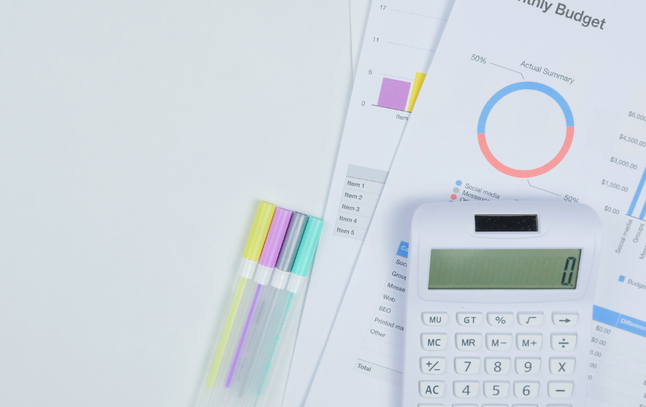 Close up of calculator, pens and printed budget sheets