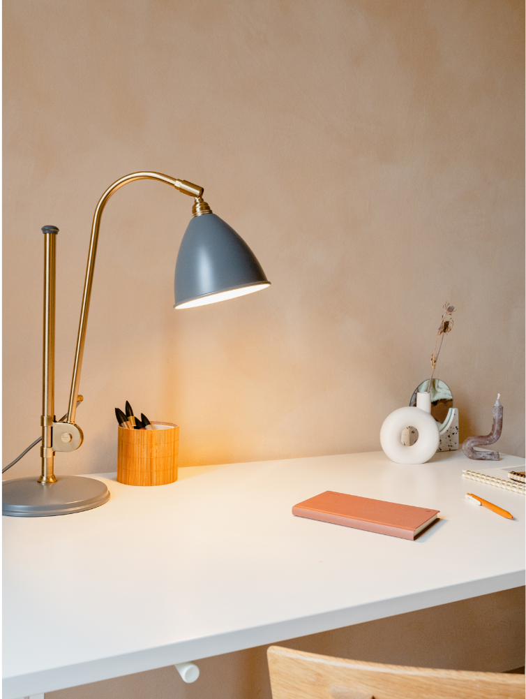 Minimalist desk with lamp, pen holder and pink notepad