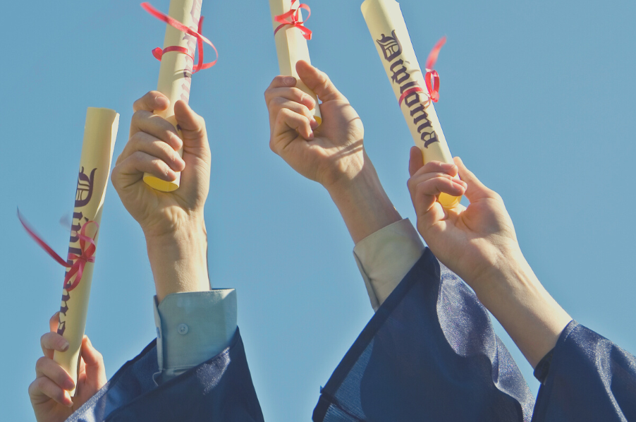 Four hands hold up their counselling diploma certificates