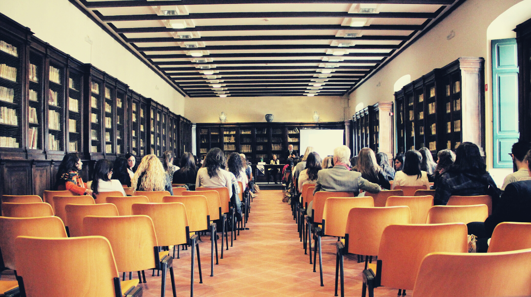 Students sit on orange seats in a lecture hall