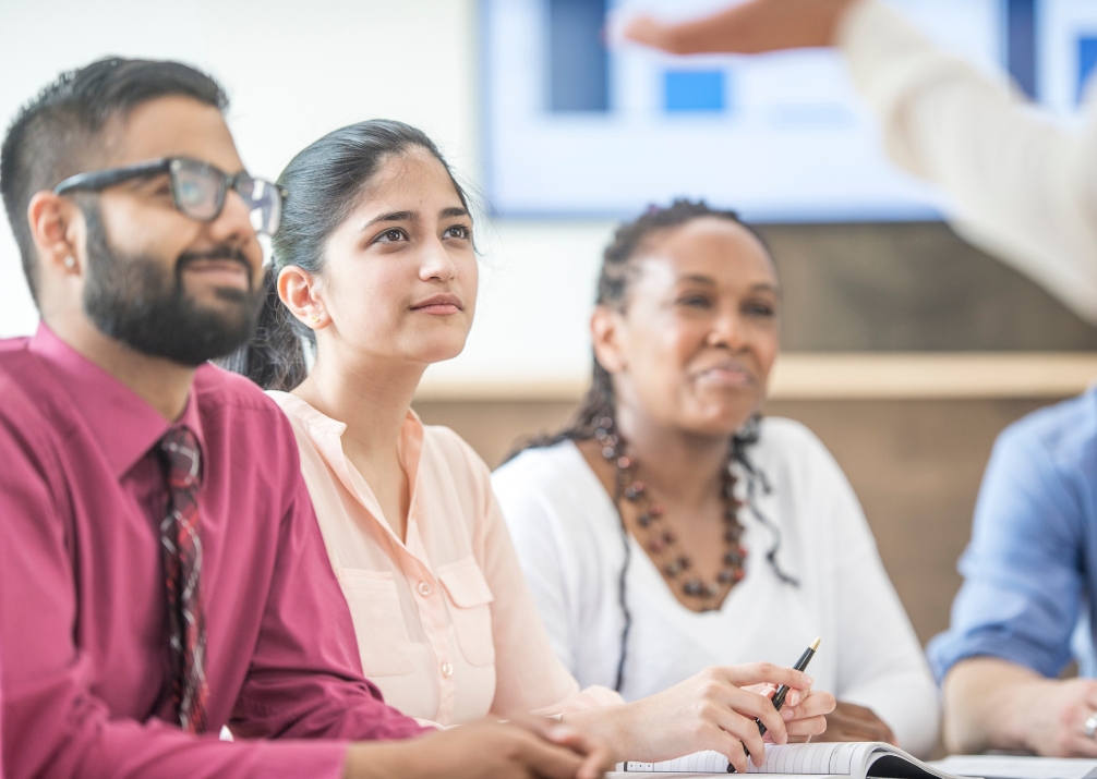 Four mature students listen to a lecturer as they continue their learning and development as counsellors