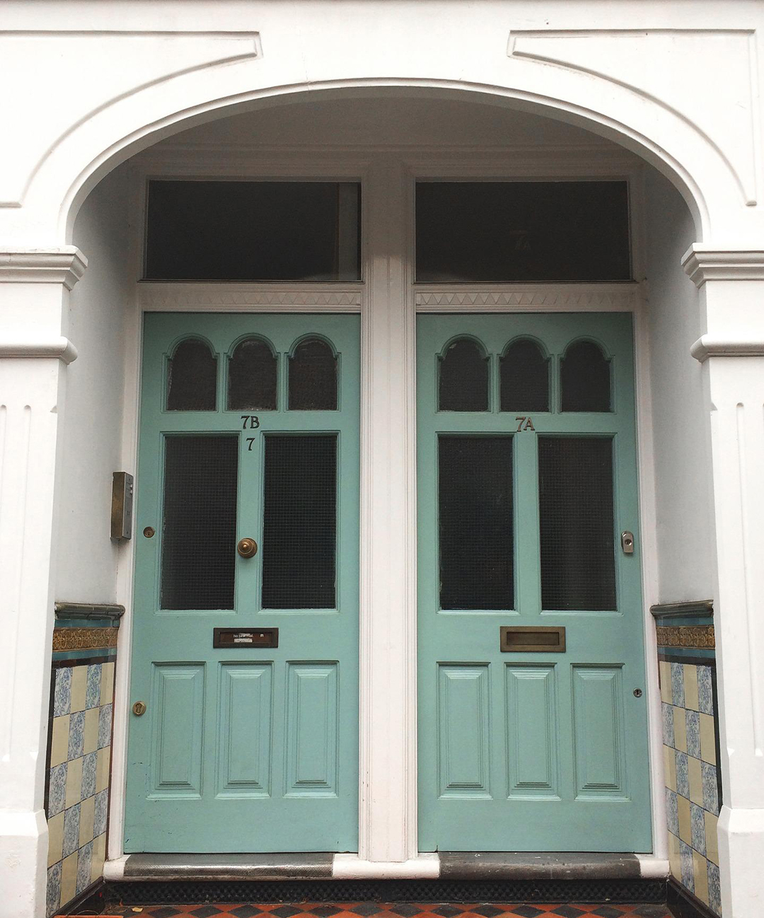 Two mint green front doors in an alcove