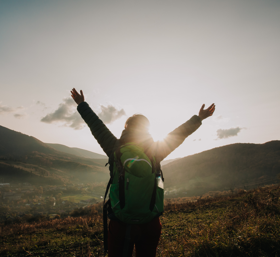 Hiker on a moor in front of mountains with hands in air in reverence