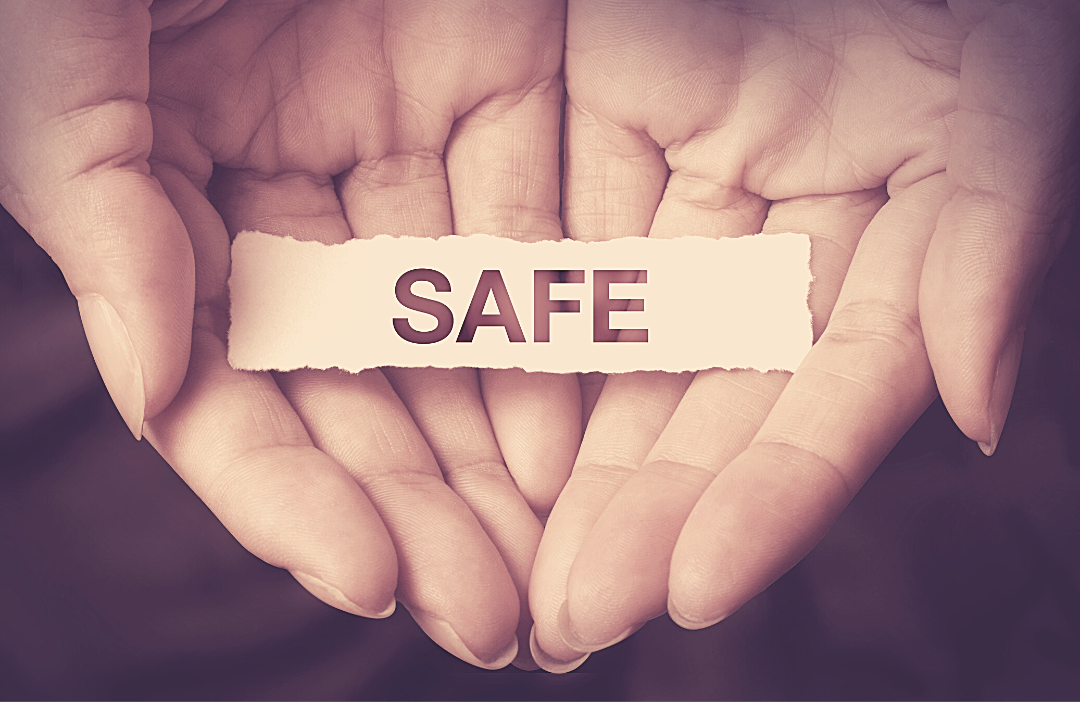 Close up of cupped hands holding a strip of paper saying the word SAFE
