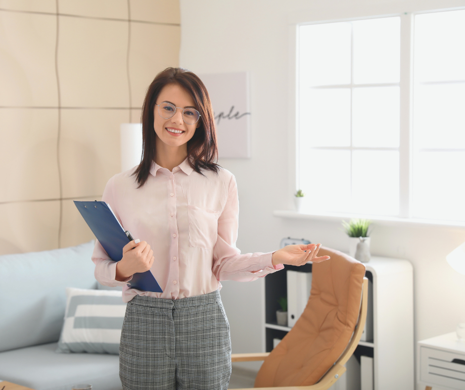 Female counsellor stands smiling in her counselling room