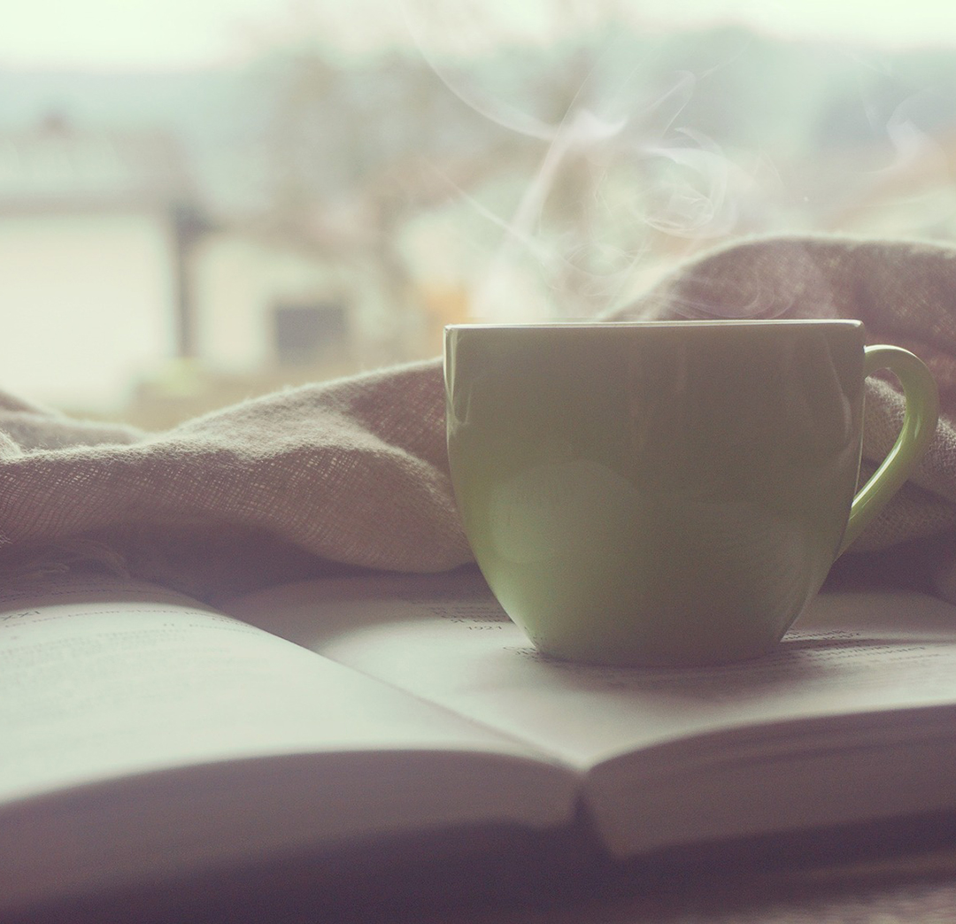 Close up of a hot cup of tea on top of an open book
