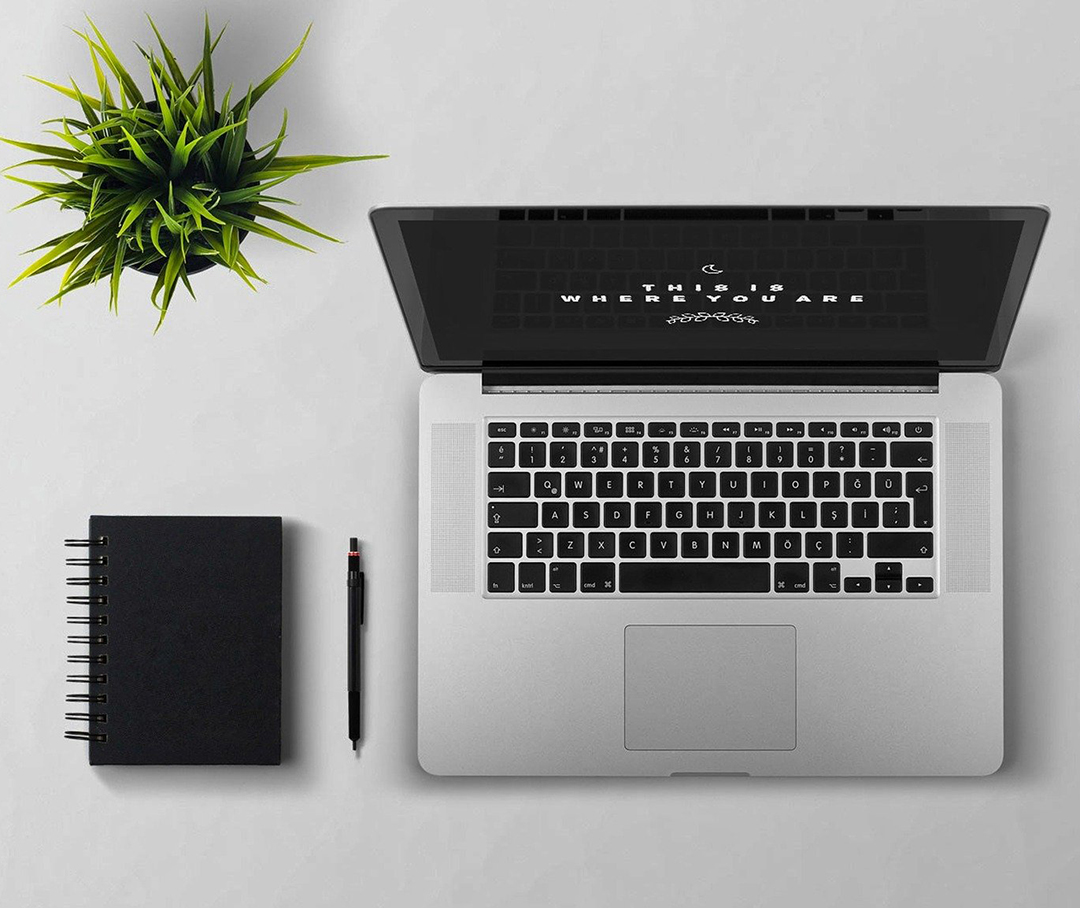 White keyboard, mouse, pen & notepad against a pink backdrop