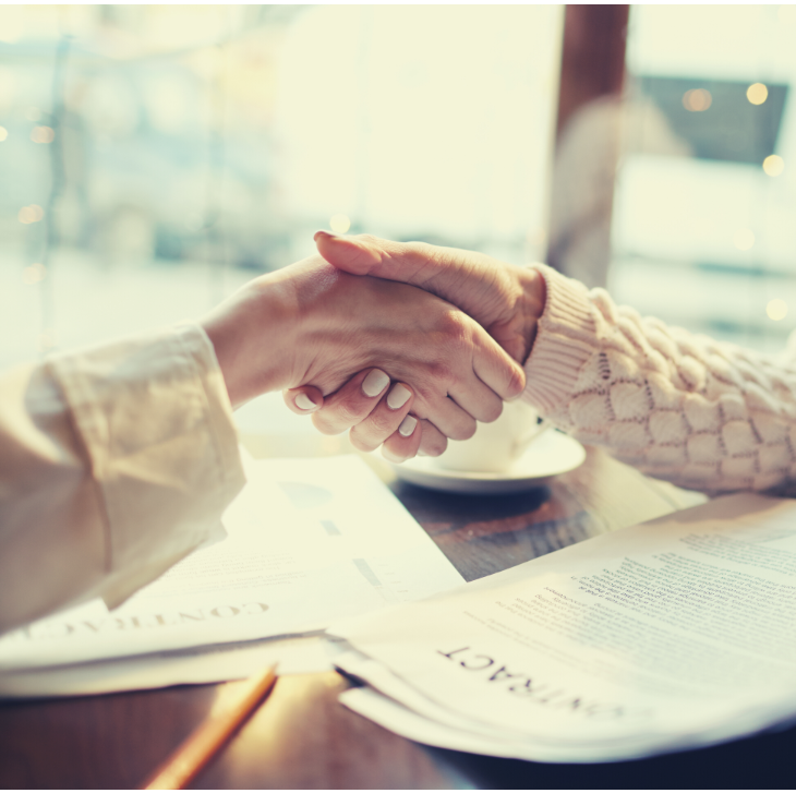 Close up of two women shaking hands over a contract