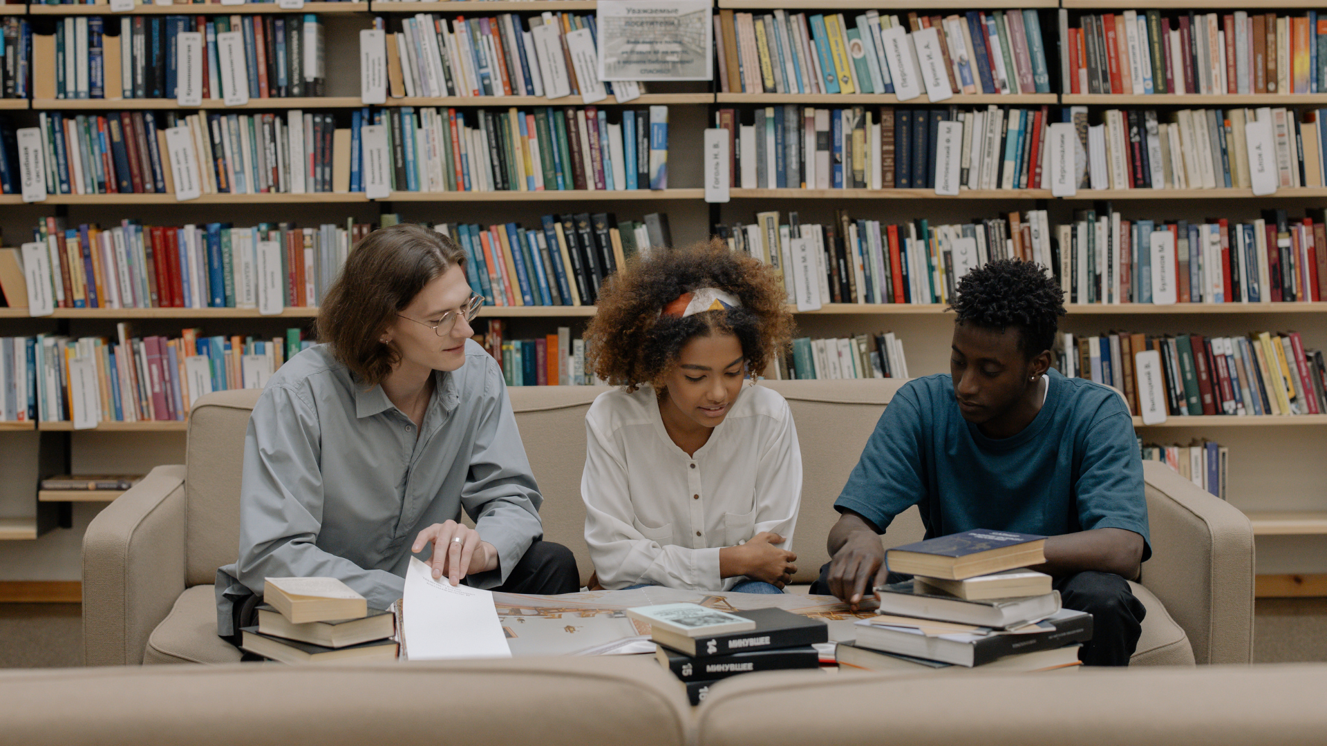 Three counselling students sit on a beige couch in the library.