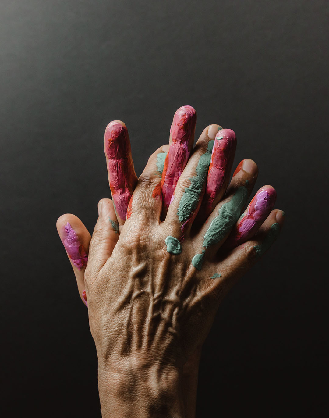 palms together covered in green and pink paint