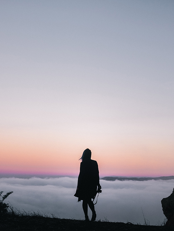 Outline of woman hiking above clouds