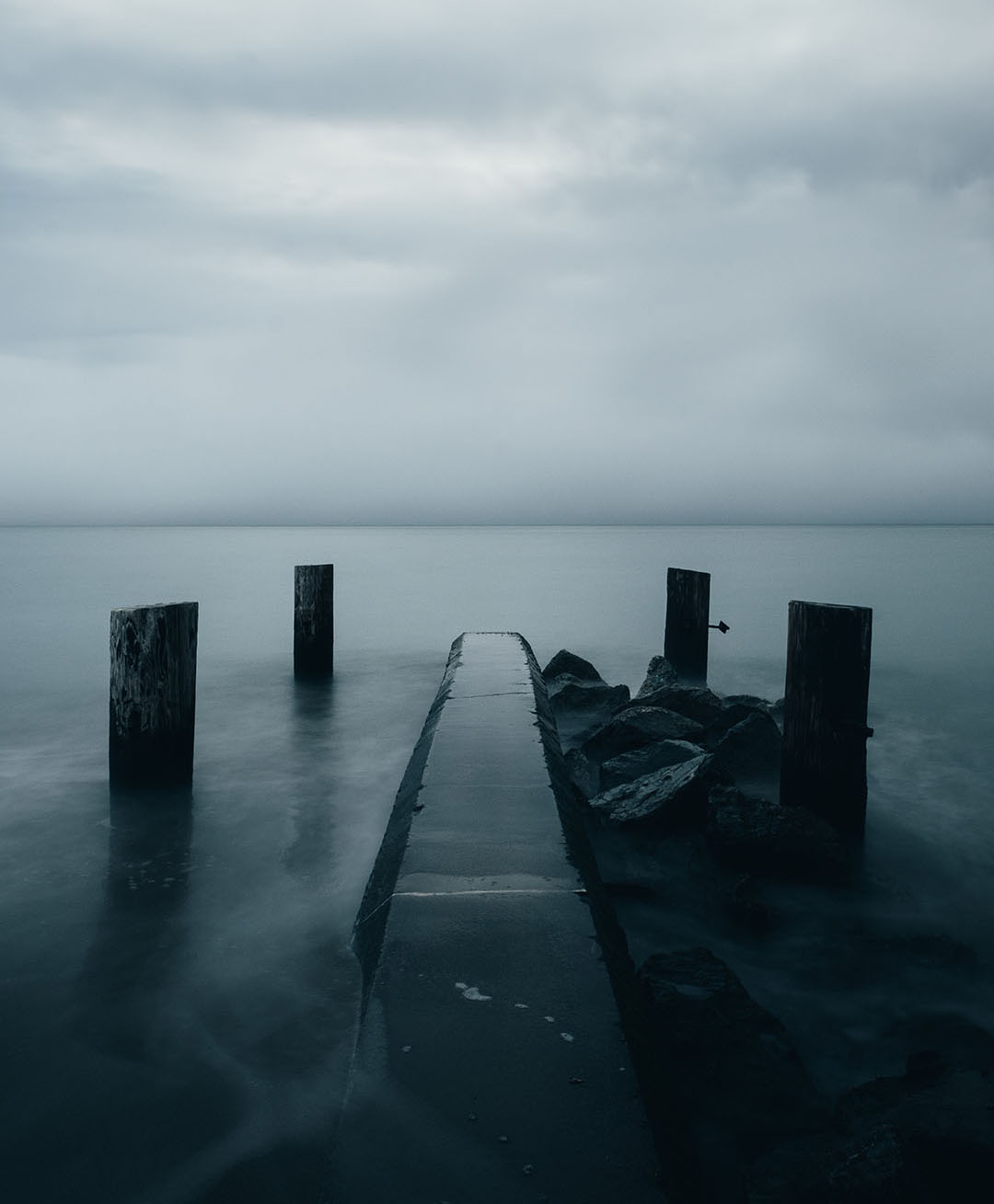 Jetty across misty waters on a cloudy day