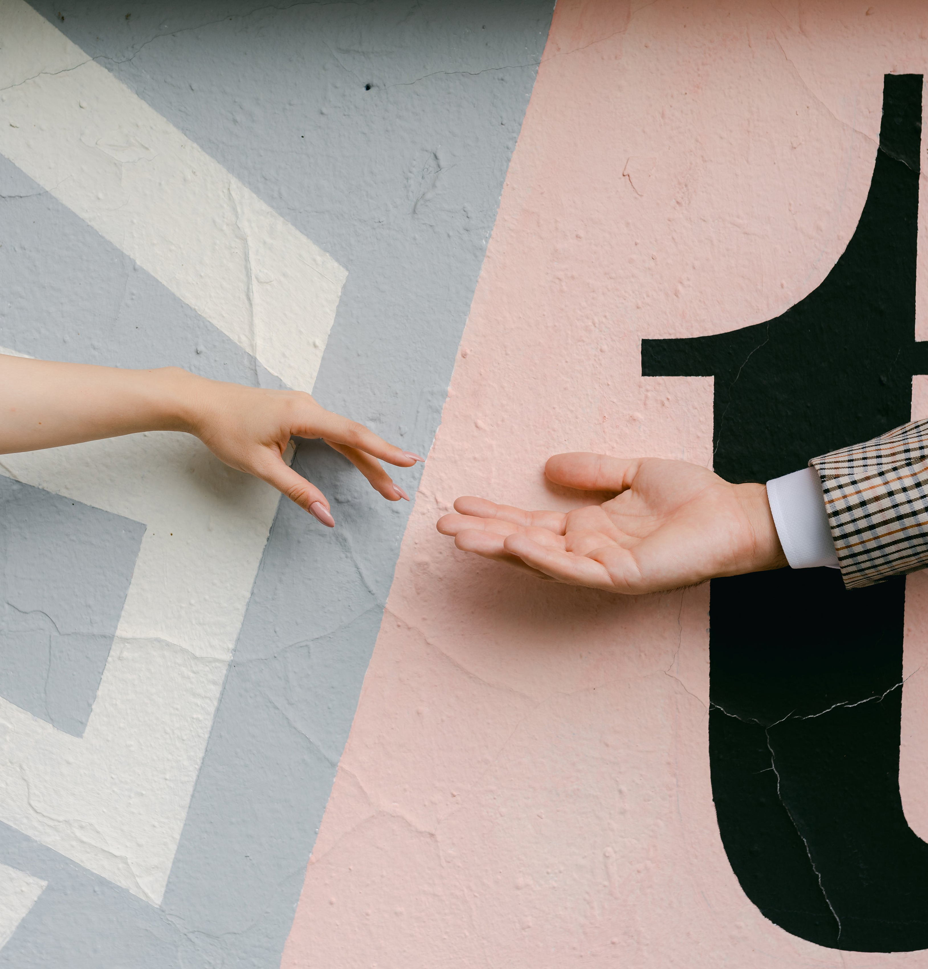 Two hands reach out for each other against a painted wall